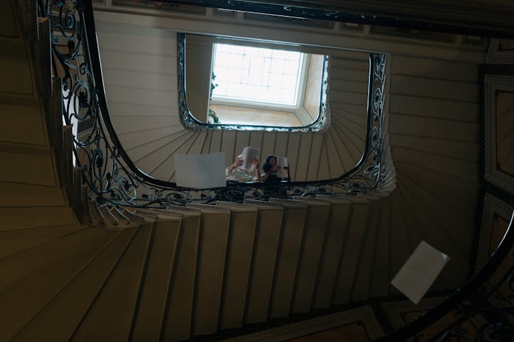 Low Angle Shot Of People Tossing Papers From A Staircase