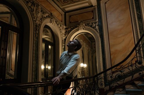 Free Man in elegant hall, gazing upward contemplatively on a spiral staircase Stock Photo