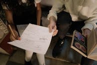 People Holding Bond Paper with Handwritten and an Open Book