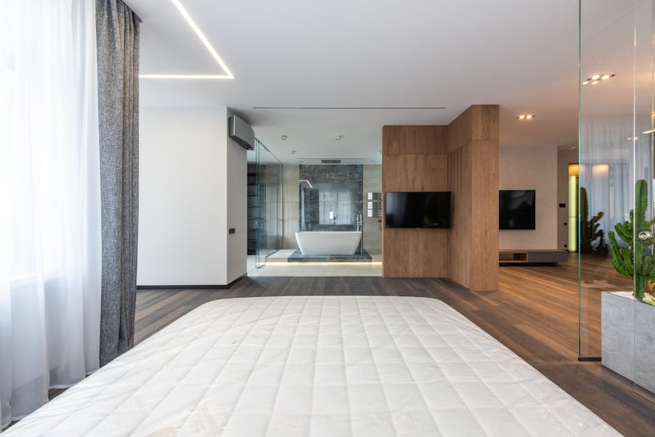 Interior of modern spacious apartment with wooden floor glass walls and bedroom looking into bathroom