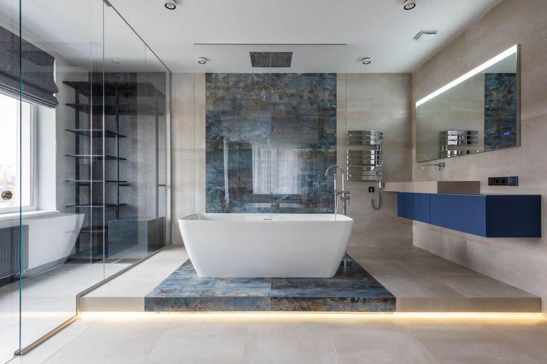 Moderne badkamer met tegelwerk in betonlook en vrijstaand bad