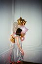 Anonymous elegant woman with assorted balloons in house