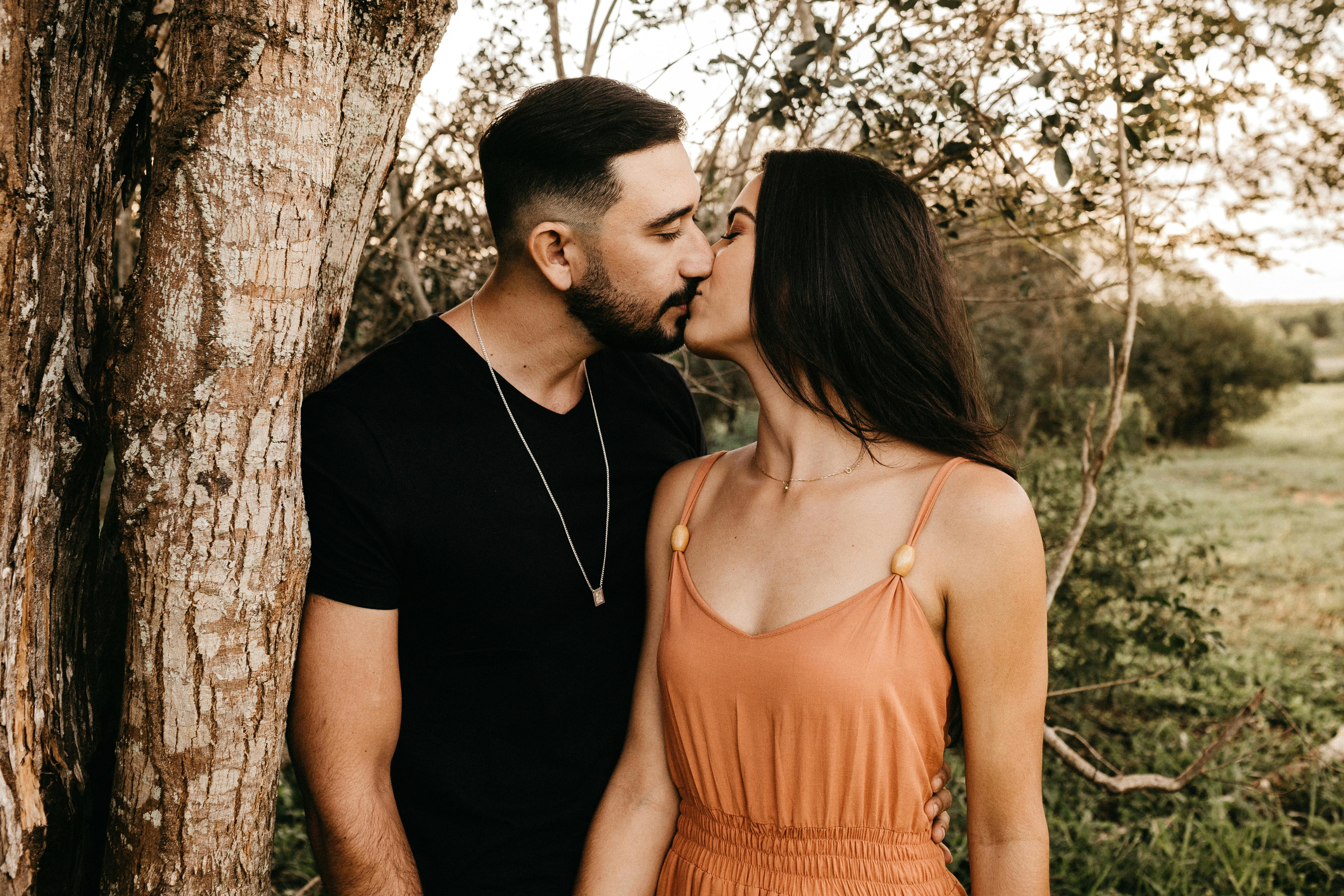 Hispanic couple kissing in countryside field in summer · Free Stock Photo