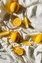 From above of bright cut and whole juicy lemons on creased bed sheet in house in sunlight