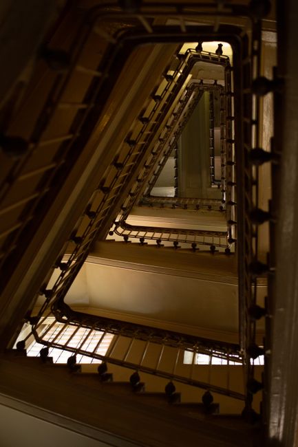From below of triangular shaped staircase with metal handrails in old building in sunlight