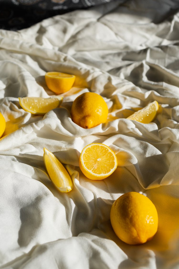 Ripe Lemons On Creased Bed Sheet In Sunlight