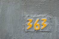 Painted yellow numbers 363 on cracked gray wall