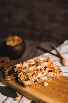 Tasty homemade granola bars with nuts and dried fruit on a wooden board, perfect for a healthy snack.