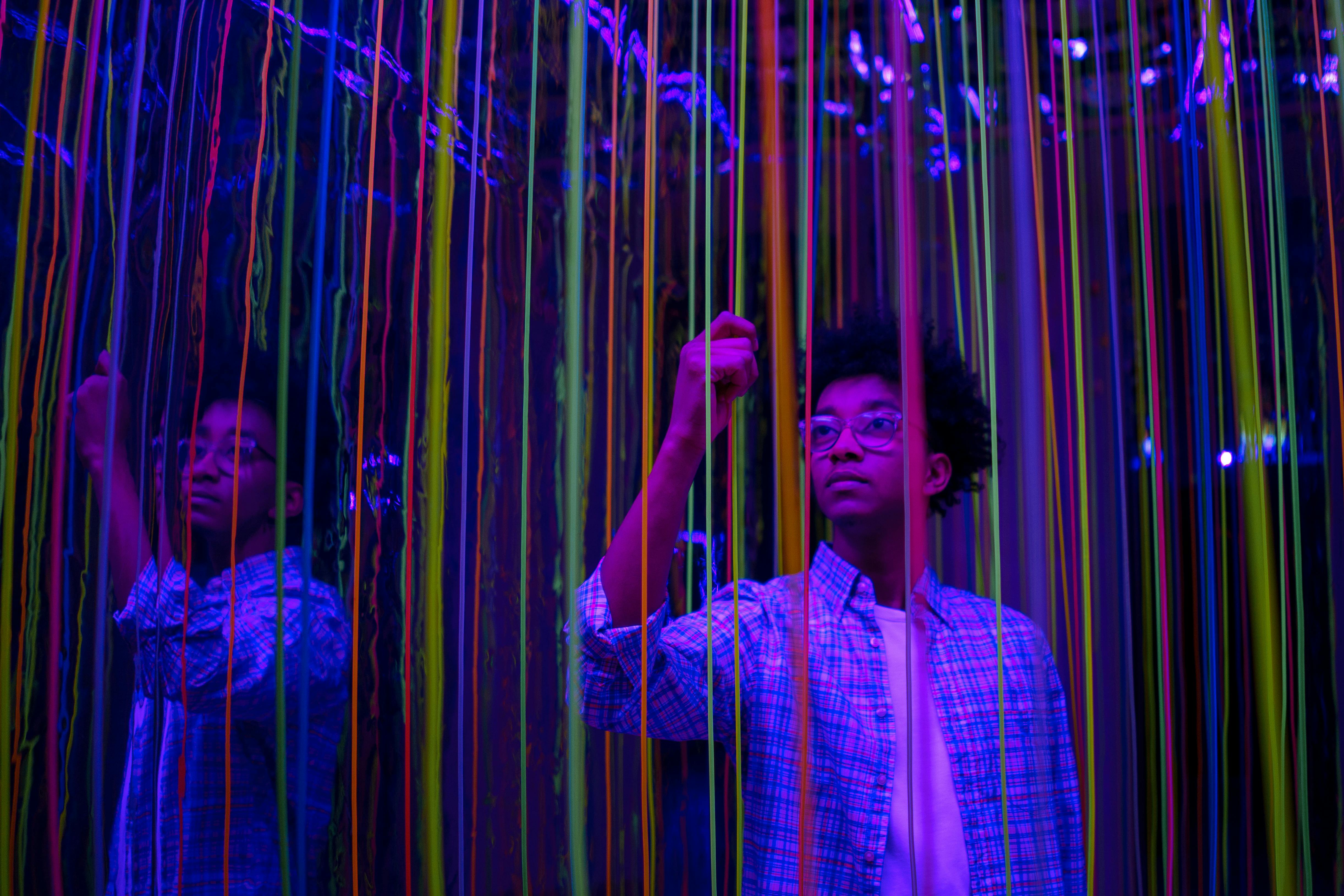 boy standing between colorful lines and mirrors
