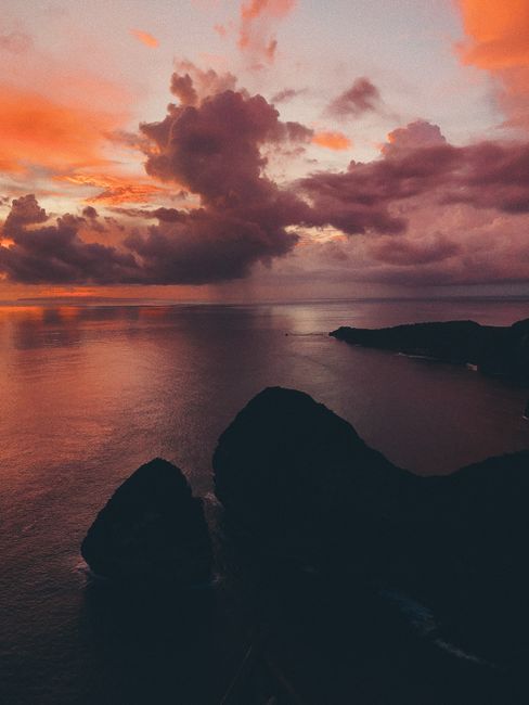 A breathtaking view of Nusapenida, Bali at sunset, capturing vibrant skies and ocean waves.