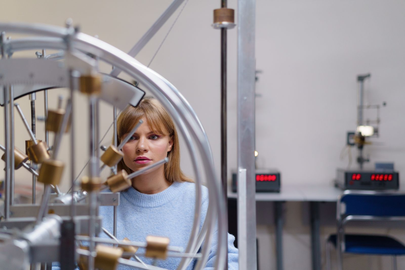 Studentessa osserva un esperimento con strumenti di fisica.