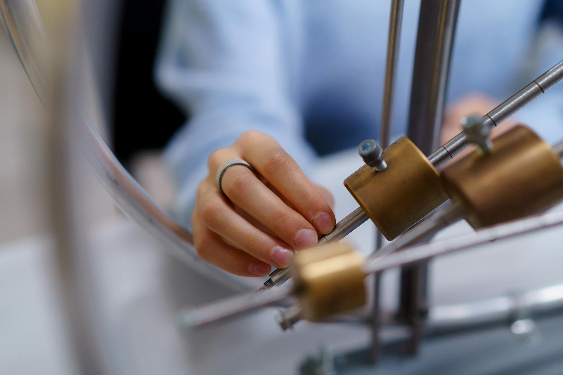 Close-up of a student's hand interacting with physics lab equipment for learning.