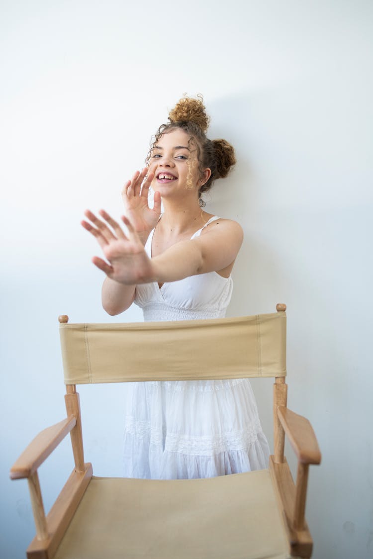 Smiling Teenage Girl Standing Behind A Folding Chair 