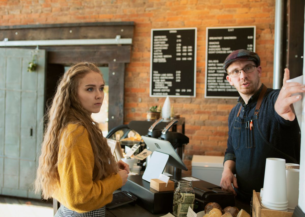 A barista helping a smiling customer at the café counter