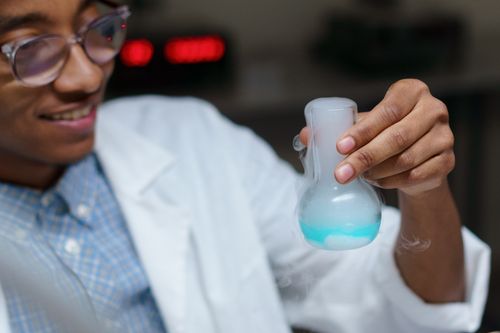 Free Close-up of a young scientist examining a chemical reaction in a laboratory. Stock Photo