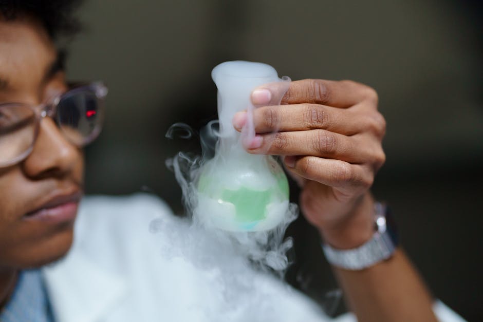 intellectual property valuation methods - Scientist examining a flask with smoke and green liquid, demonstrating a laboratory chemical reaction.