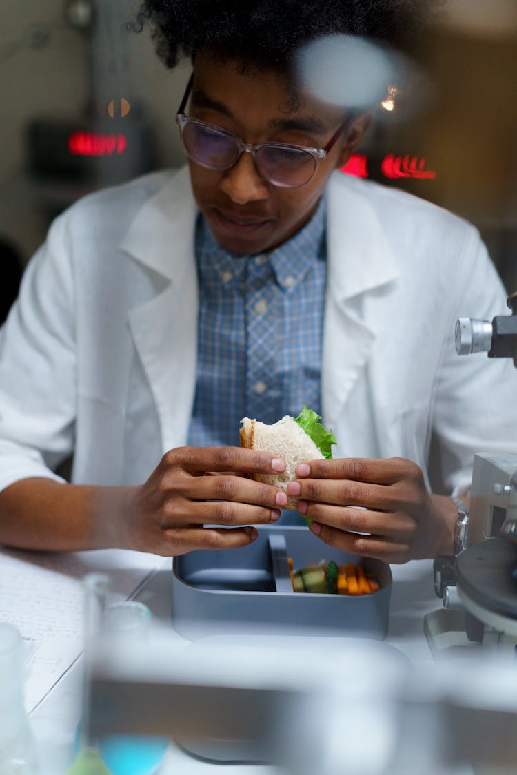 Man In White Lab Coat Eating Sandwich