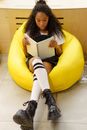 Woman in Black Leather Boots Sitting on Yellow Chair