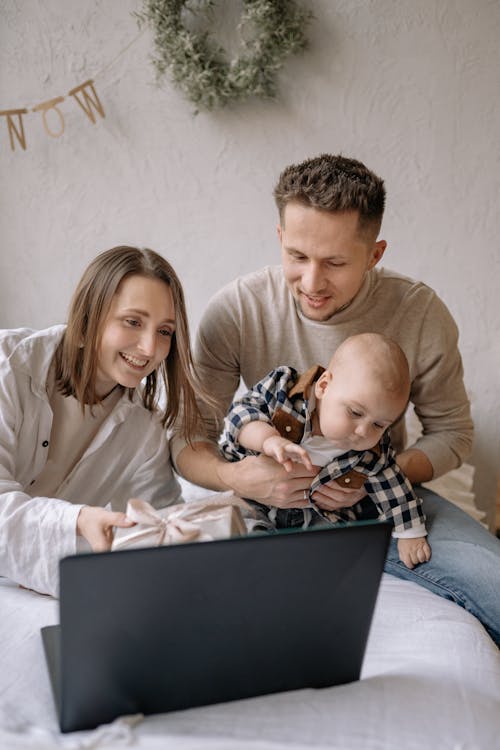 Couple Sitting on Bed with Their Son while Having a Video Call on Laptop