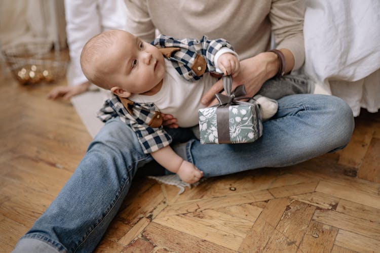 A Cute Baby Holding A Gift