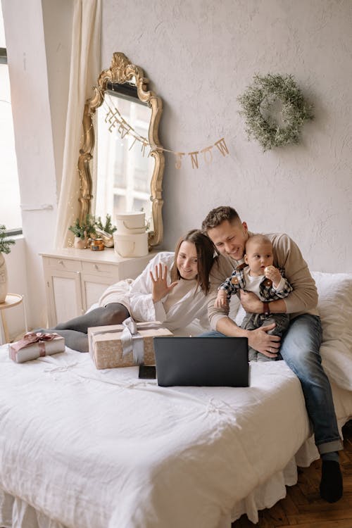 Free Couple Sitting on Bed with Their Son while Looking at a Laptop Stock Photo