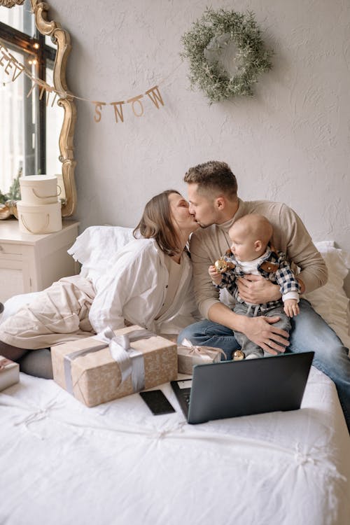 Free Couple Kissing while Sitting on Bed Stock Photo