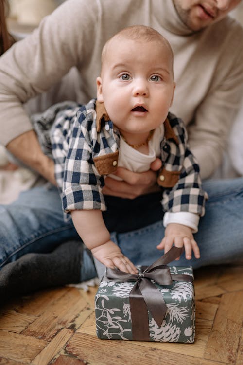 Close-Up Photo of a Cute Baby Touching a Gift