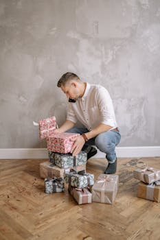 Young man in white shirt arranging colorful wrapped presents indoors.