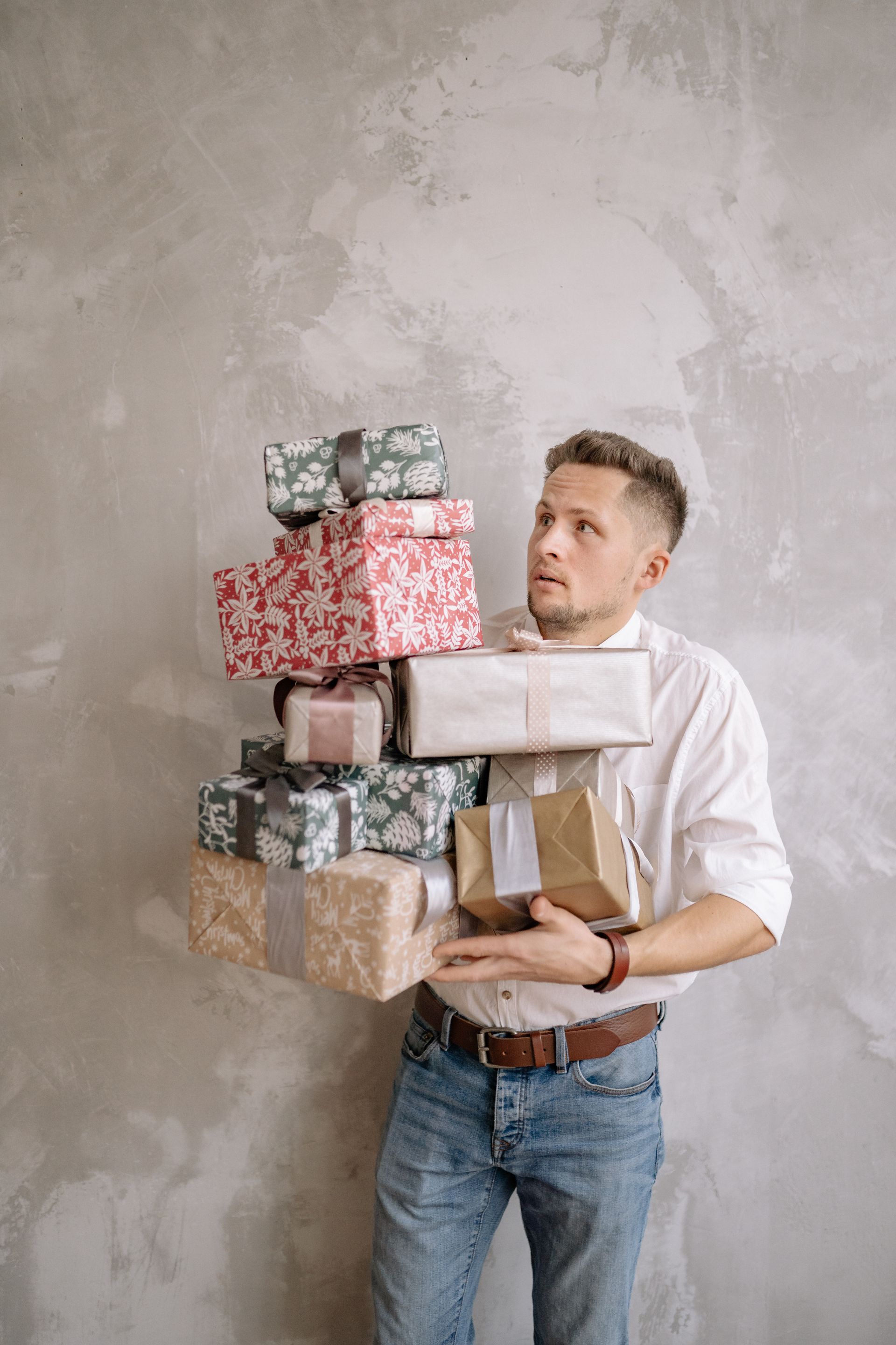 Man struggling to carry a stack of wrapped gift boxes