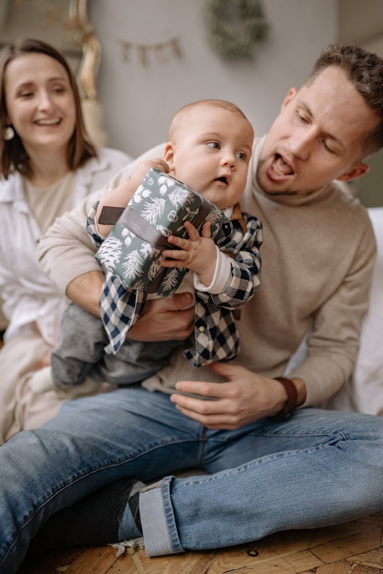 Couple Smiling With A Baby Holding A Gift 