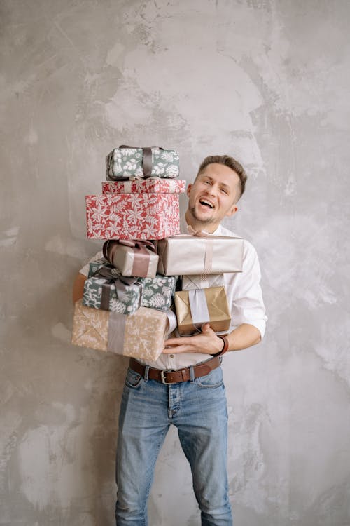 Man Smiling While Carrying Boxes of Gifts