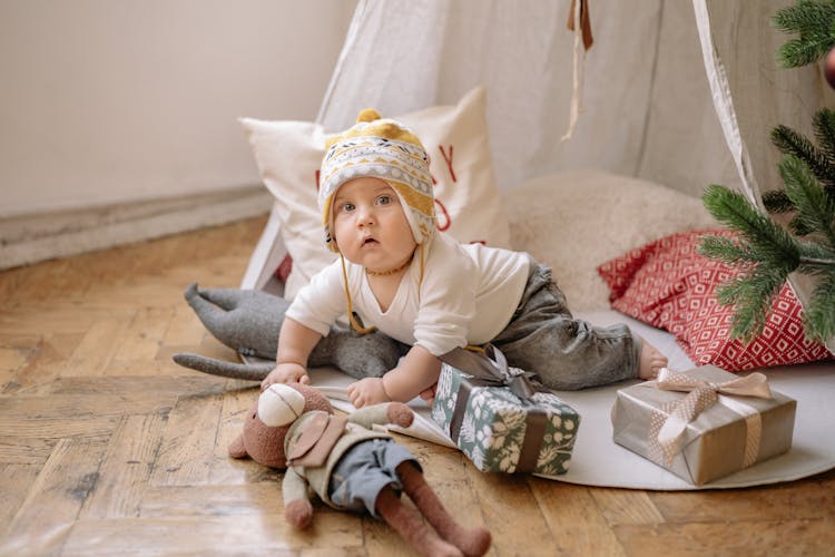 Baby Holding A Teddy Bear Beside Christmas Gifts