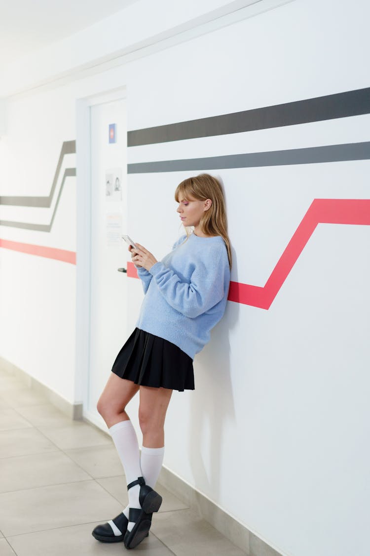 Pretty Woman Leaning On A Wall While Using A Cellphone