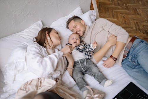 Free Couple with Their Son Lying Down on Bed Stock Photo