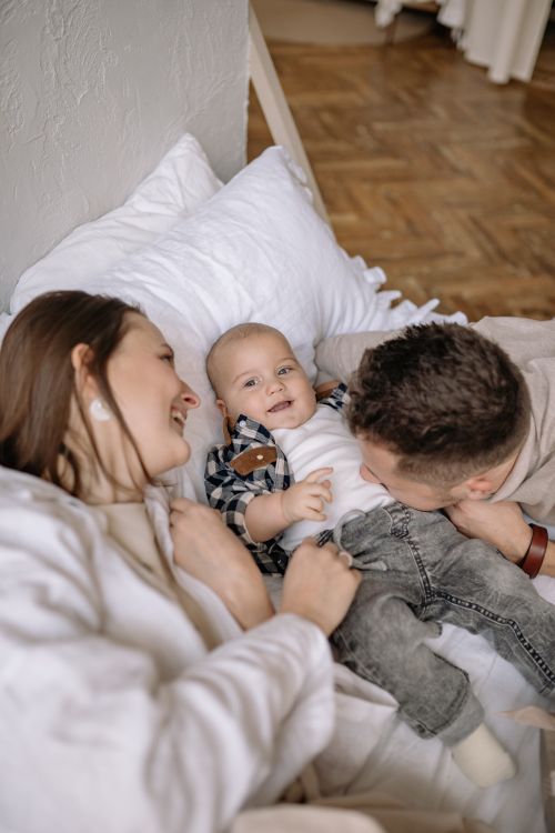 Free Joyful family moments with parents and baby on the bed, capturing love and closeness. Stock Photo