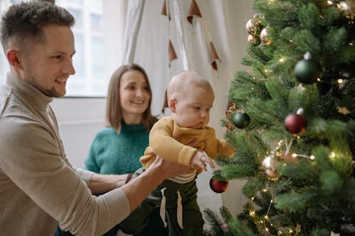 Family Sitting Beside a Green Christmas Tree