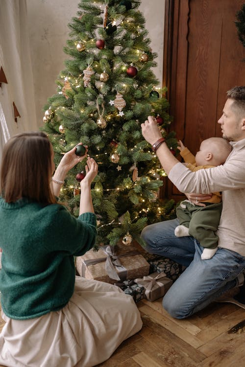 Free A Man and a Woman Decorating a Christmas Tree Stock Photo