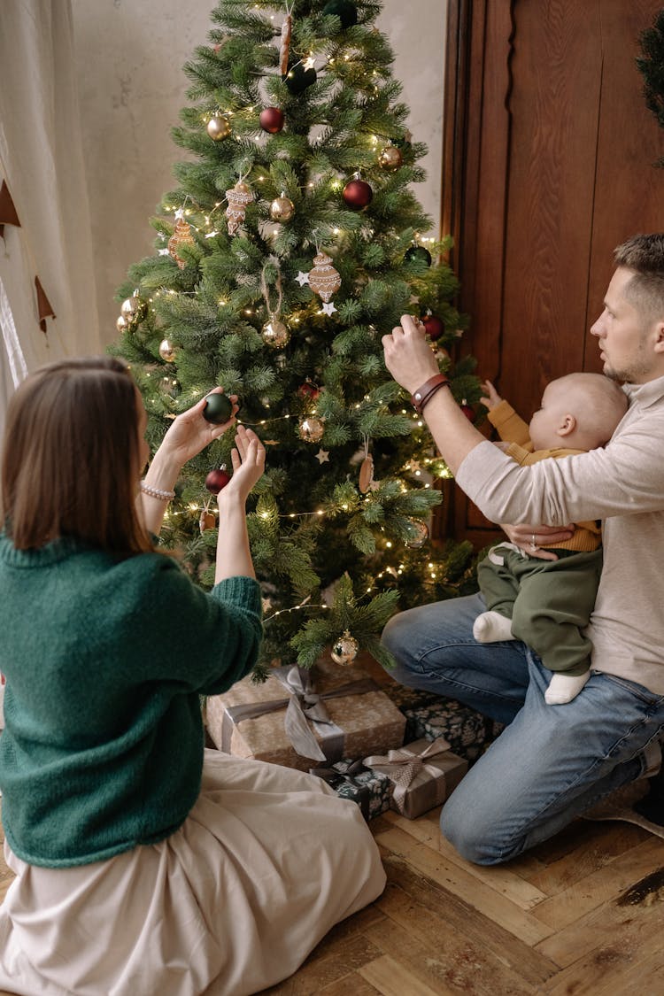 A Man And A Woman Decorating A Christmas Tree