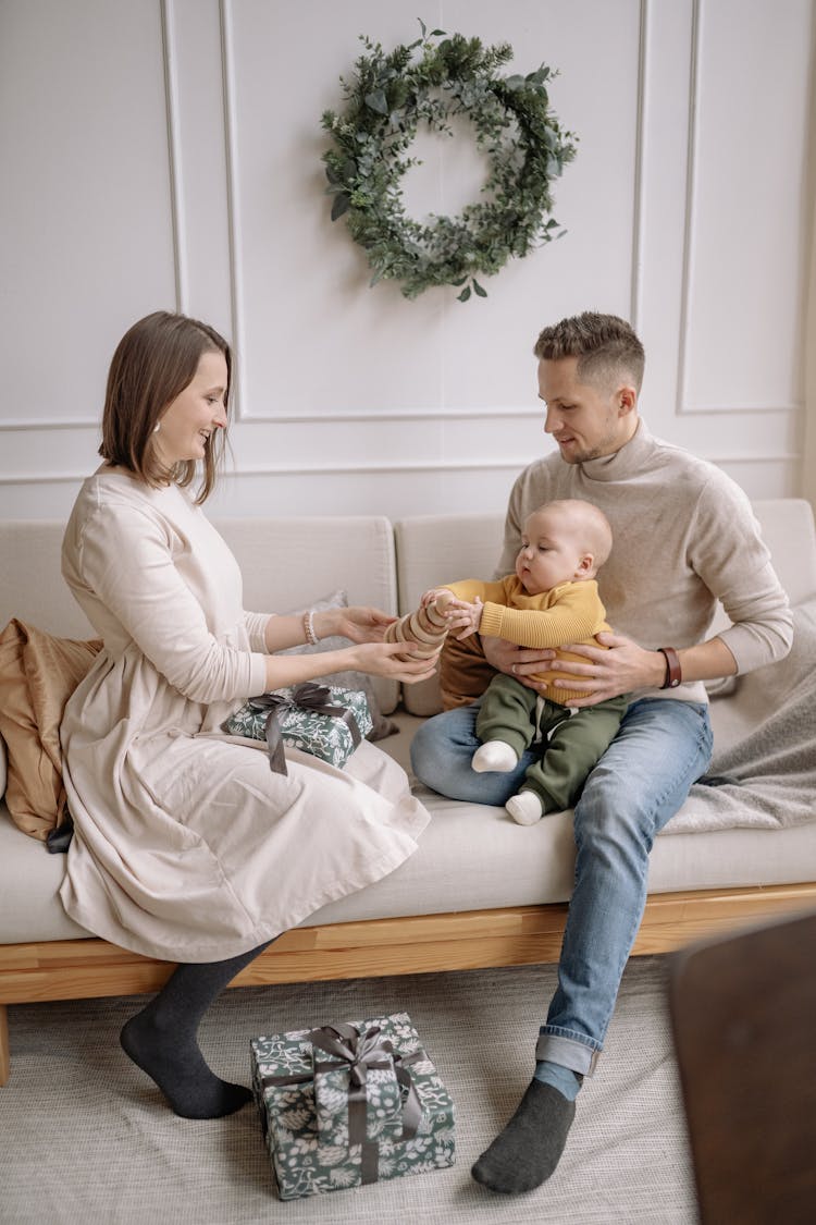 A Mother Handing A Wooden Toy To A Baby