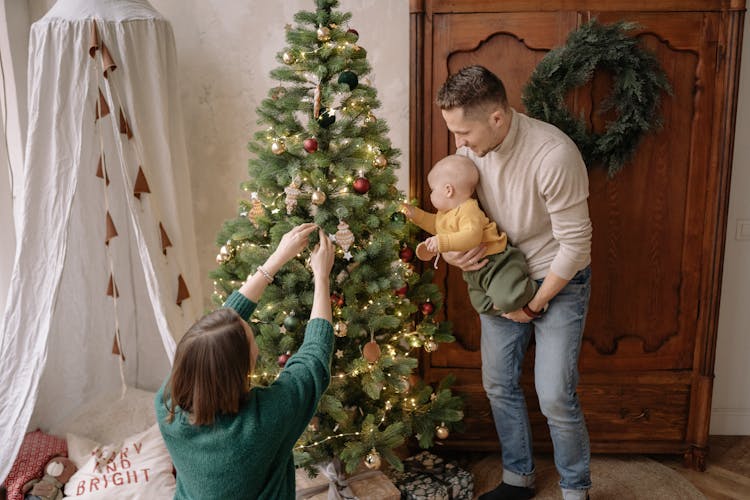 Family With A Little Baby Decorating A Christmas Tree 