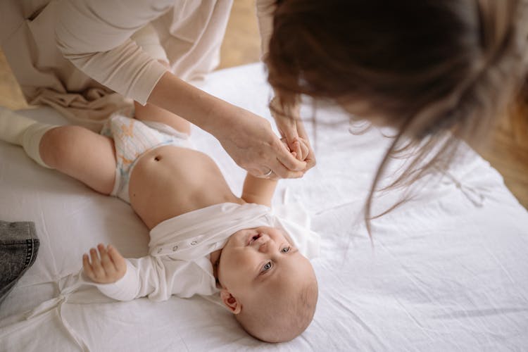 A Mother Taking Off A Baby's Onesie