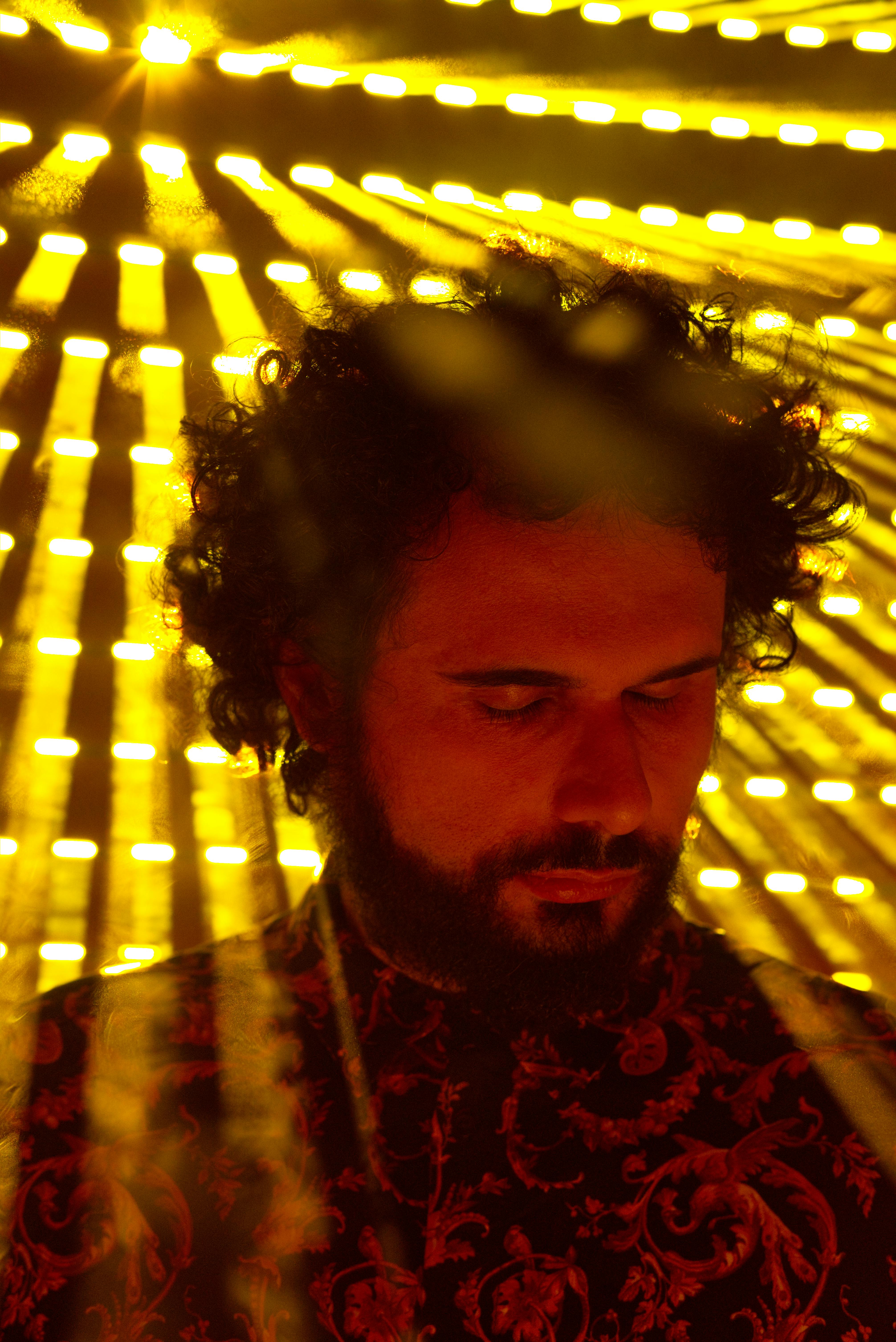 Dramatic portrait of a man in vibrant yellow backlighting creating an artistic effect.