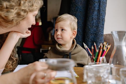 Free A mother and child engaging in creative drawing time with colored pencils at a cozy indoor setting. Stock Photo