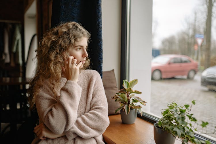 Woman Talking Through The Phone And Looking Out The Window