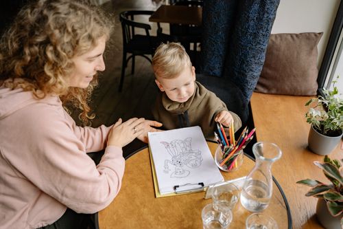 Free A mother and son drawing together at a table, fostering creativity and bonding. Stock Photo