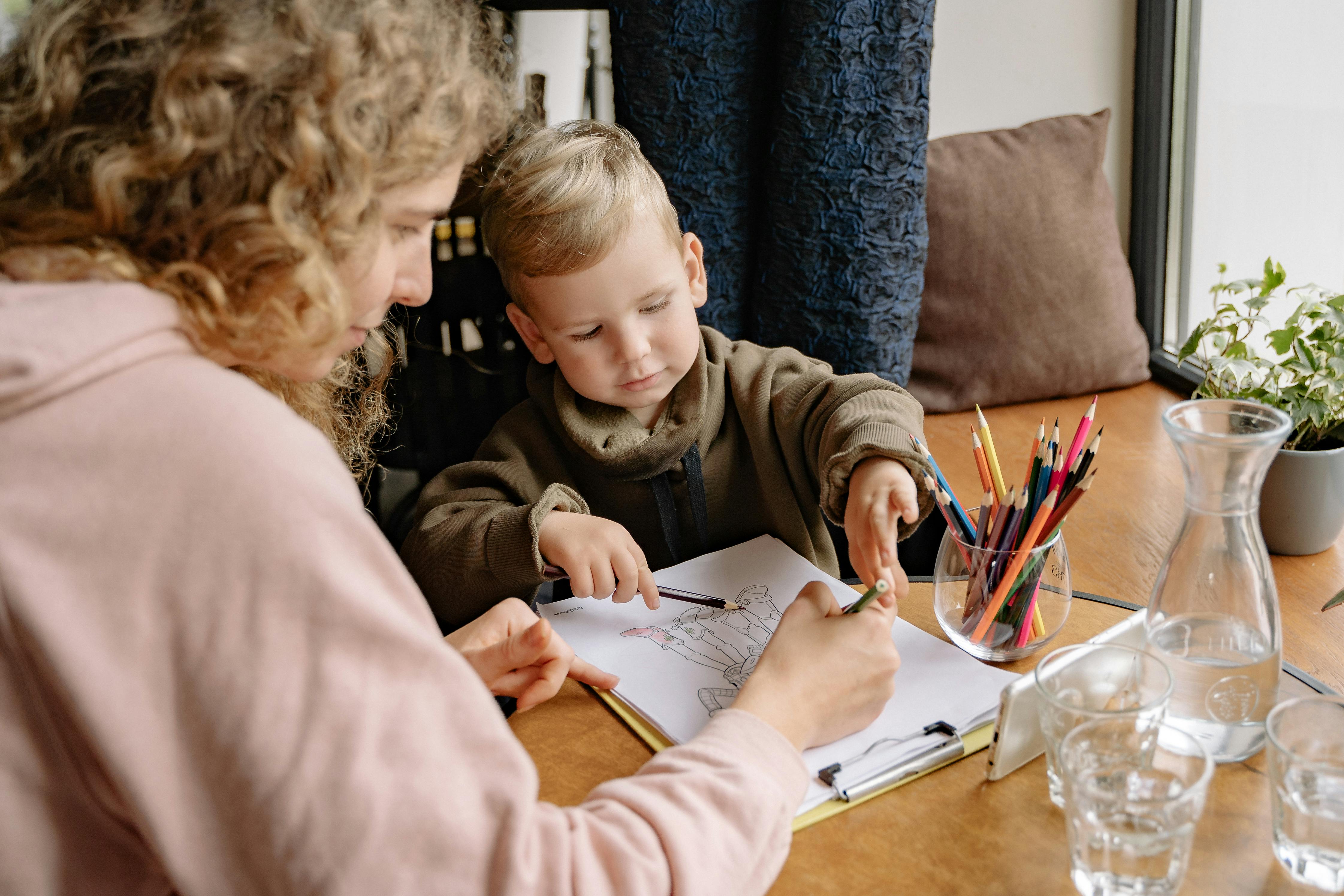 a woman teaching a boy to draw