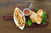 木桌上摆着美味的烤奶酪三明治，配上酥脆的薯条和蘸酱