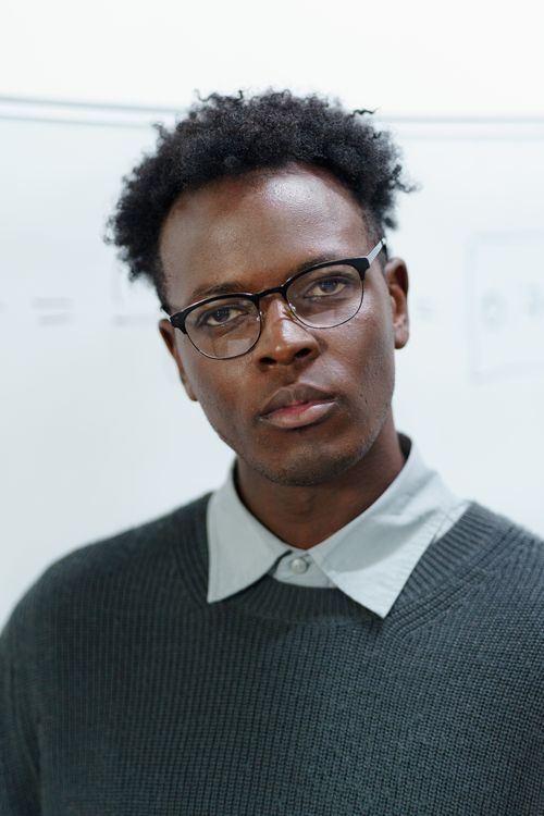 Free A serious-looking man with glasses wears a gray sweater indoors. Stock Photo
