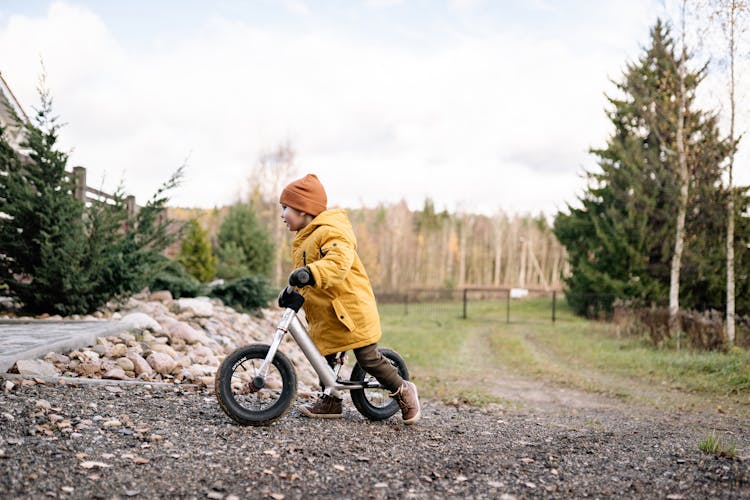 A Young Kid In Yellow Jacket Riding A Bicycle