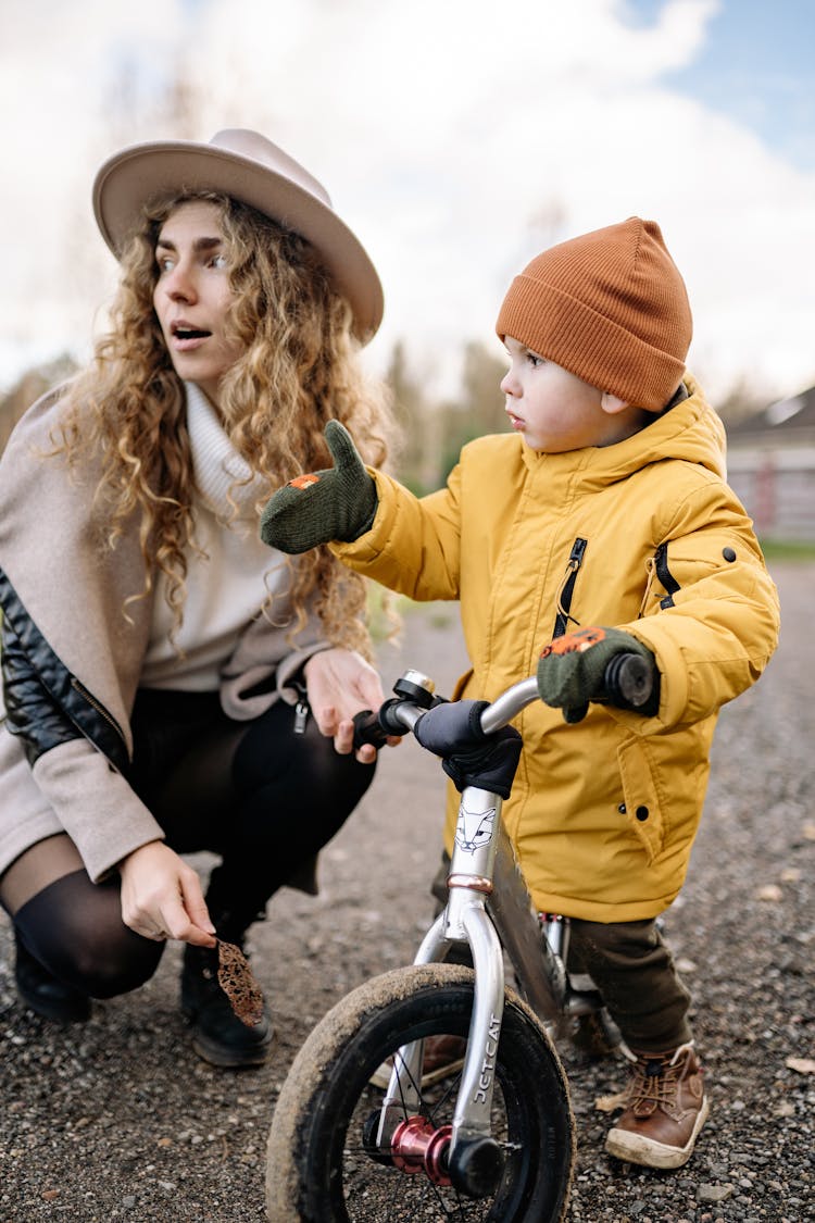 A Child Wearing Jacket And Gloves While Riding A Bike